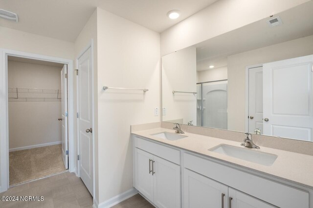 bathroom featuring visible vents, a sink, a walk in closet, and a shower stall