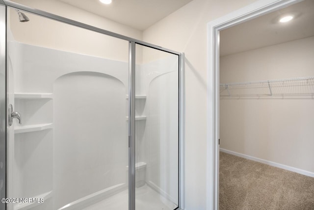 bathroom featuring a walk in closet, baseboards, a stall shower, and recessed lighting