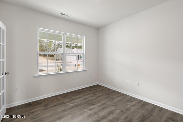 unfurnished room with baseboards, visible vents, and dark wood-style floors