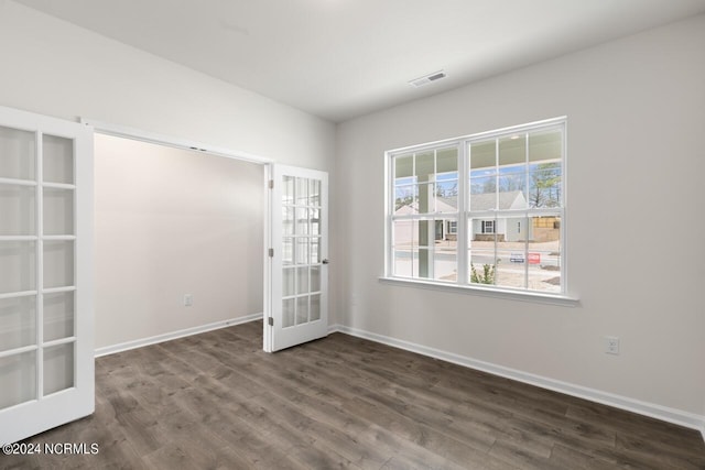 unfurnished room with visible vents, dark wood-style flooring, baseboards, and french doors