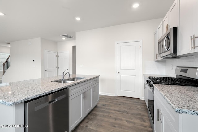 kitchen featuring visible vents, dark wood-style flooring, a center island with sink, a sink, and stainless steel appliances