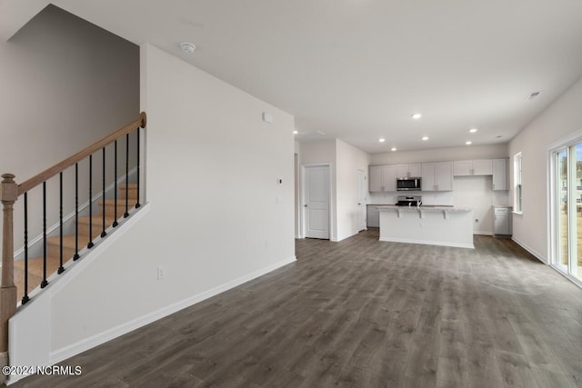 unfurnished living room featuring baseboards, recessed lighting, stairs, and dark wood-type flooring