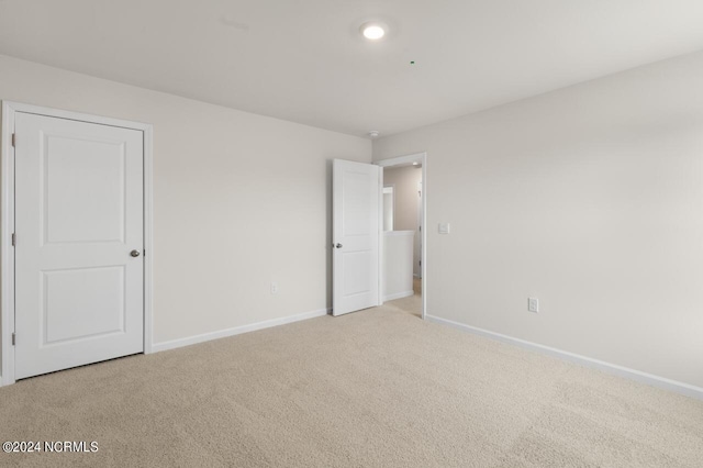 unfurnished bedroom featuring baseboards and light carpet