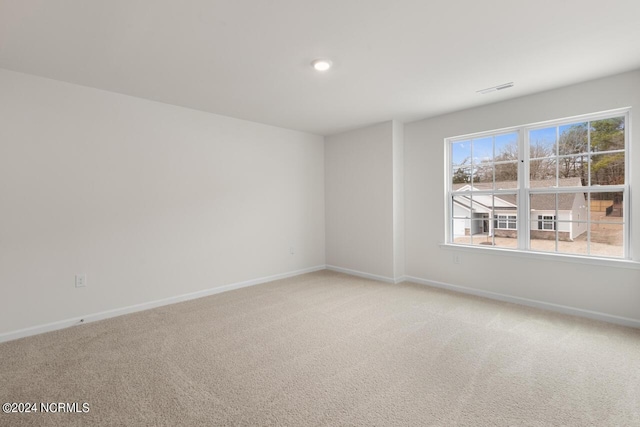 empty room with light colored carpet, baseboards, and visible vents