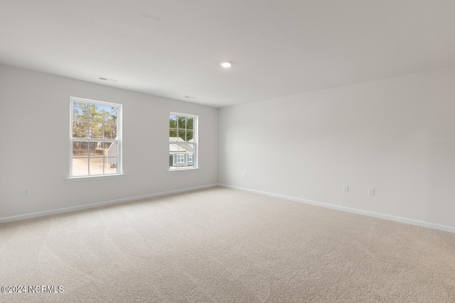unfurnished room featuring light colored carpet and baseboards