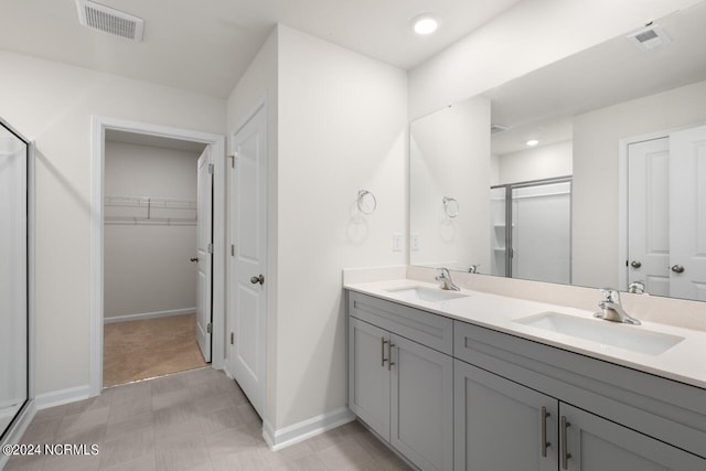 full bathroom featuring double vanity, baseboards, a sink, and a stall shower