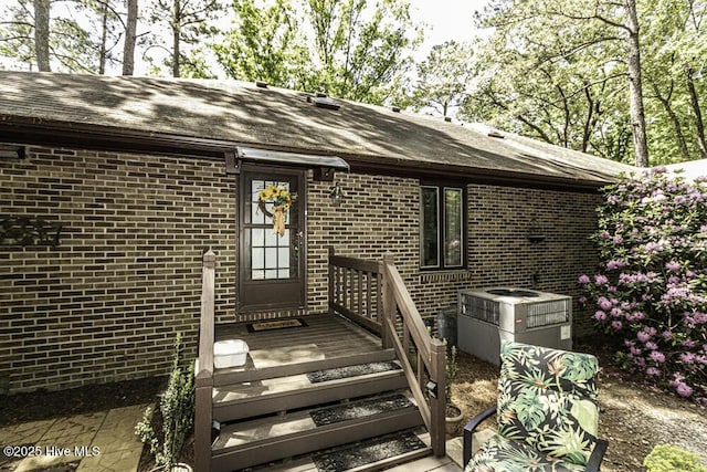 7730 Old Raleigh Rd, Bailey, NC 27807 - view of exterior entry featuring a shingled roof, brick siding, and central AC