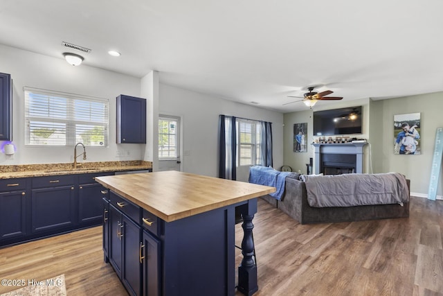 kitchen featuring a sink, butcher block counters, open floor plan, a breakfast bar area, and blue cabinets