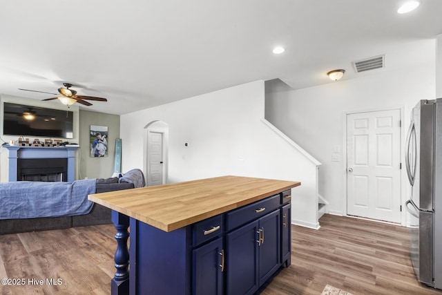 kitchen featuring ceiling fan, wooden counters, freestanding refrigerator, visible vents, and blue cabinets