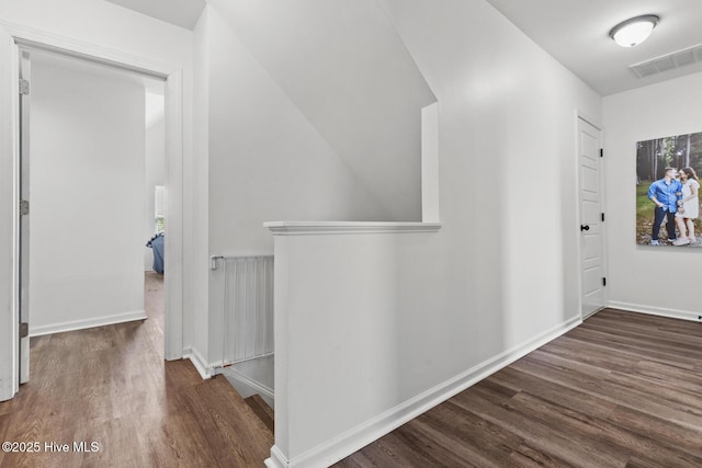hall featuring baseboards, an upstairs landing, a healthy amount of sunlight, wood finished floors, and visible vents