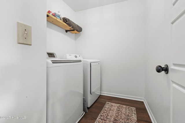 clothes washing area featuring dark wood-style flooring, laundry area, washing machine and dryer, and baseboards