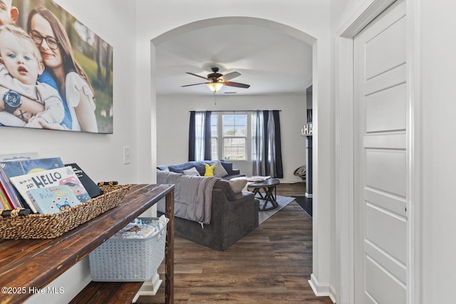 hallway featuring arched walkways and dark wood finished floors