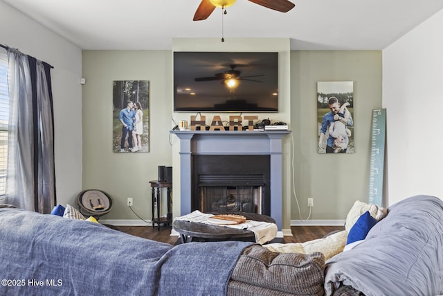 living area with baseboards, ceiling fan, a fireplace, and wood finished floors