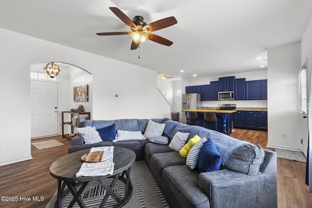 living room featuring dark wood-style flooring, a ceiling fan, recessed lighting, and arched walkways