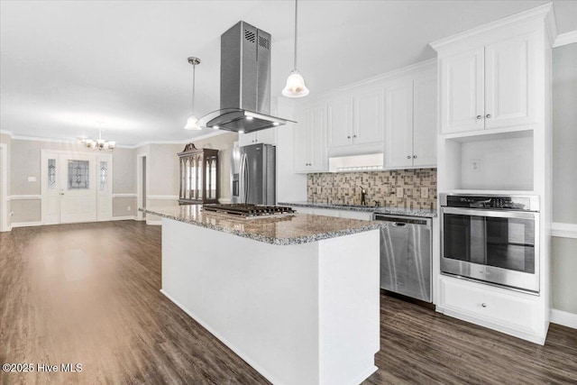 kitchen with exhaust hood, decorative backsplash, appliances with stainless steel finishes, a center island, and a notable chandelier