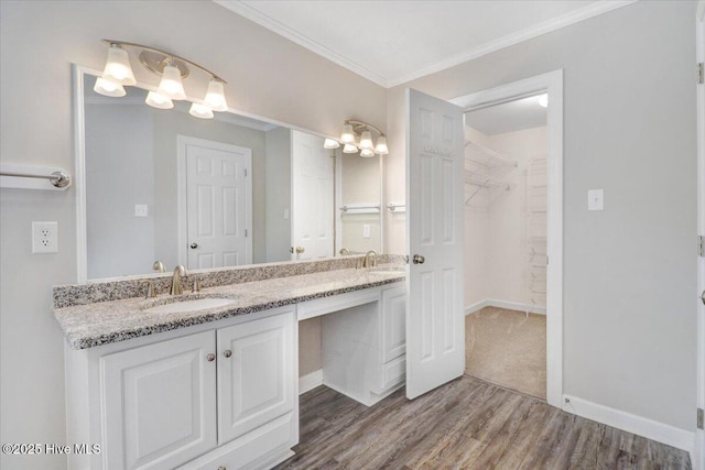 full bathroom with double vanity, a walk in closet, crown molding, wood finished floors, and a sink