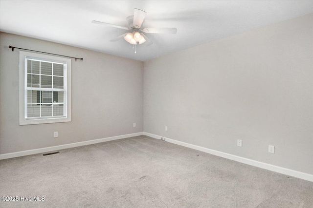 carpeted spare room featuring baseboards, a ceiling fan, and visible vents