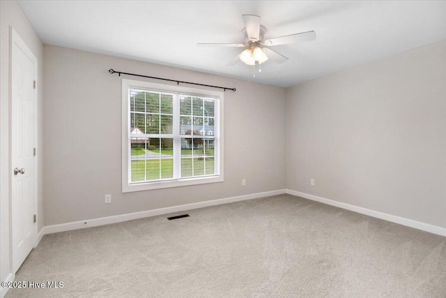 carpeted empty room with visible vents, a ceiling fan, and baseboards