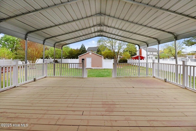 deck featuring a storage shed, a yard, a fenced backyard, and a carport