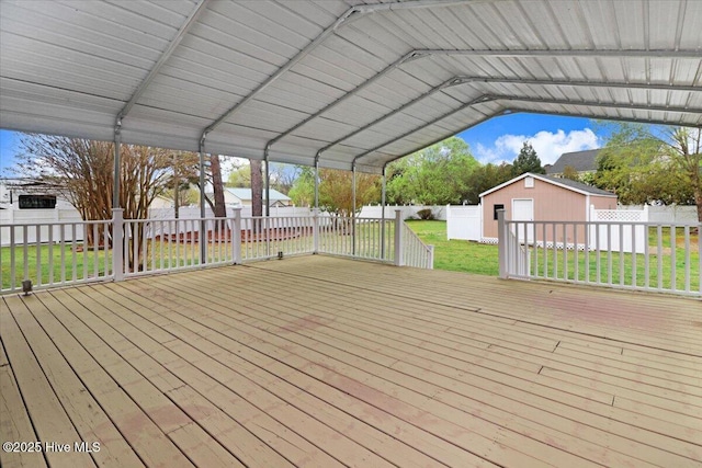 deck with an outdoor structure, a fenced backyard, a shed, a lawn, and a carport