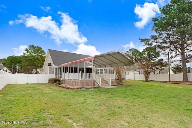 rear view of house with a fenced backyard, a detached carport, a sunroom, and a lawn