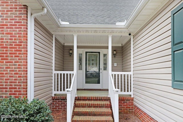 property entrance with a porch, brick siding, and roof with shingles