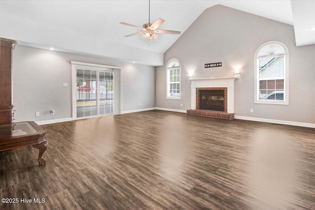 unfurnished living room featuring plenty of natural light, a ceiling fan, a brick fireplace, and wood finished floors