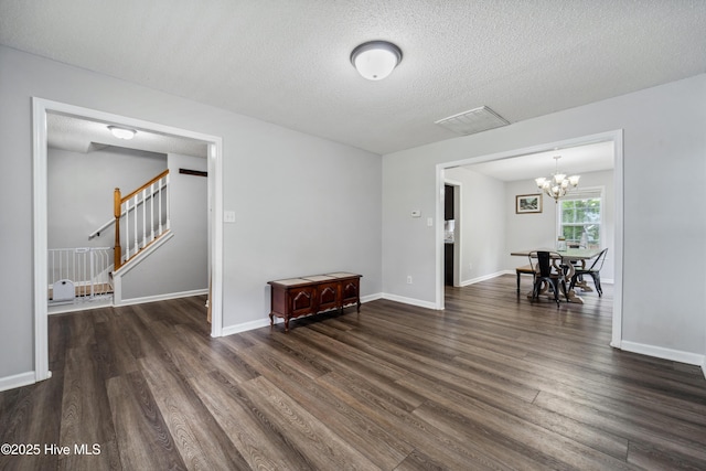 living area with an inviting chandelier, visible vents, dark wood-style flooring, and stairs