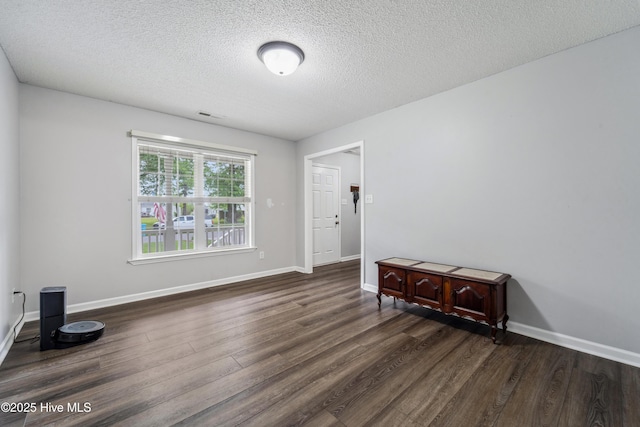 empty room featuring baseboards, a textured ceiling, visible vents, and wood finished floors