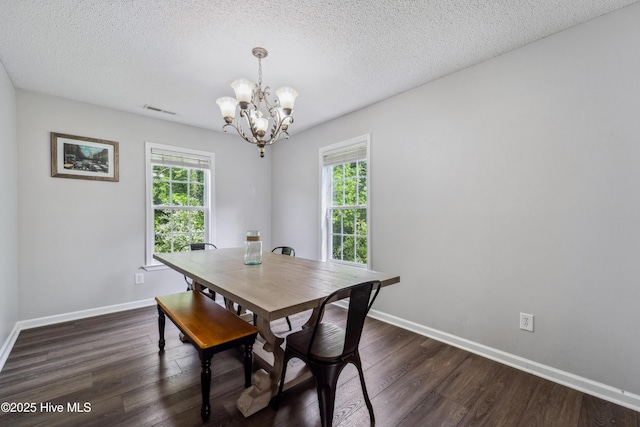 dining space featuring dark wood-style flooring, a textured ceiling, visible vents, baseboards, and an inviting chandelier