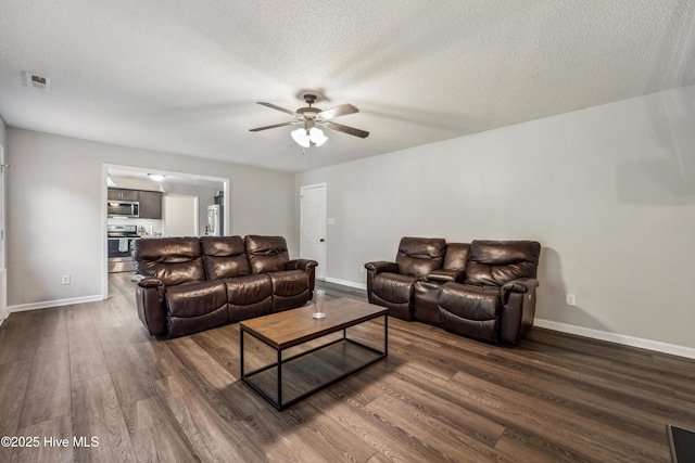 living room with baseboards, a textured ceiling, dark wood-style flooring, and ceiling fan