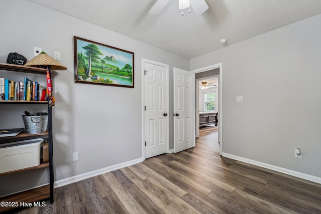 unfurnished bedroom featuring a textured ceiling, baseboards, a ceiling fan, and wood finished floors