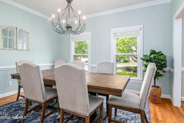 dining area with crown molding, light wood-type flooring, and a notable chandelier