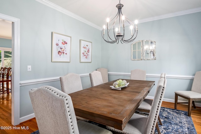 dining space featuring ornamental molding, a notable chandelier, baseboards, and wood finished floors