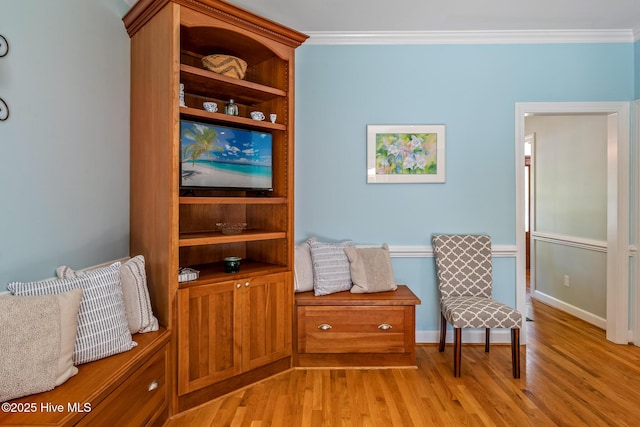 living area featuring light wood-type flooring, baseboards, and crown molding
