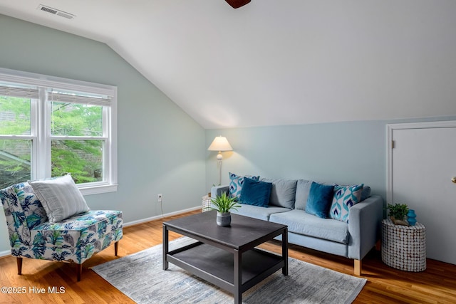 living area featuring lofted ceiling, baseboards, visible vents, and wood finished floors