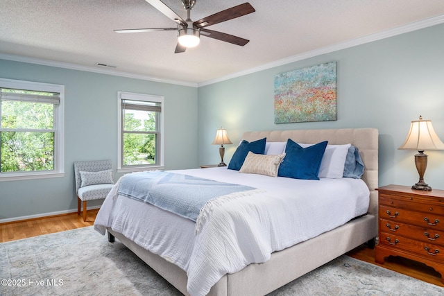 bedroom with wood finished floors, a ceiling fan, visible vents, baseboards, and ornamental molding