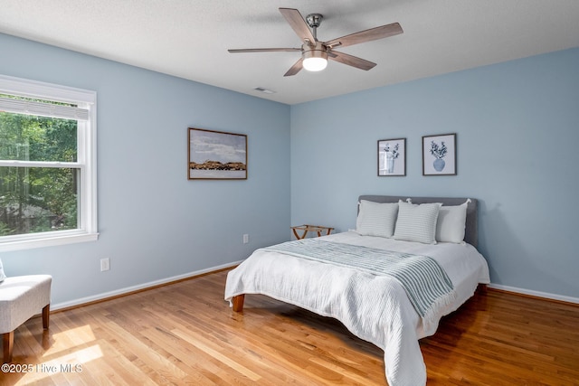 bedroom with ceiling fan, light wood-style flooring, baseboards, and visible vents