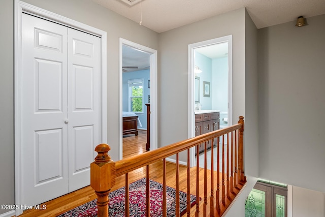 corridor featuring light wood-style flooring, attic access, and an upstairs landing