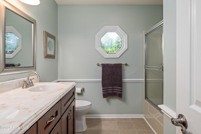 full bath featuring toilet, baseboards, bath / shower combo with glass door, tile patterned flooring, and vanity