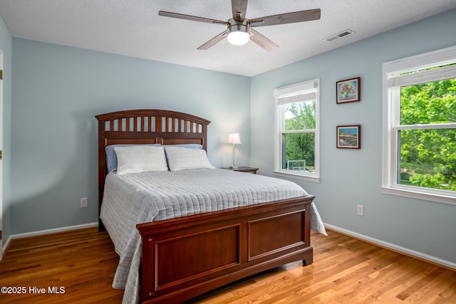 bedroom featuring ceiling fan, baseboards, visible vents, and light wood-style floors