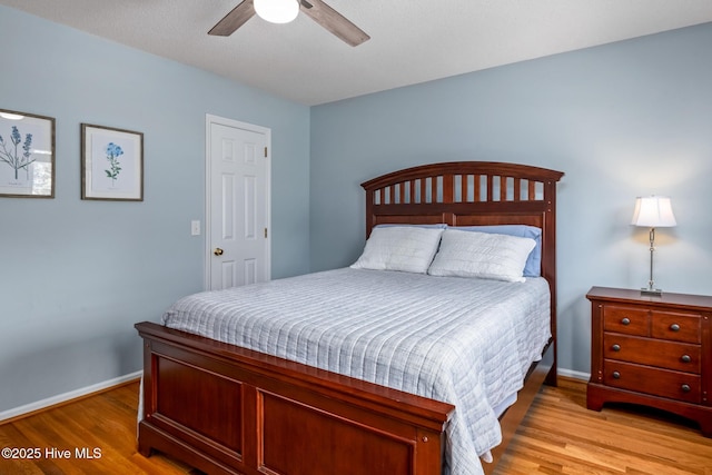 bedroom featuring baseboards, light wood-type flooring, and a ceiling fan