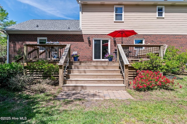rear view of house featuring a shingled roof, brick siding, stairway, and a wooden deck