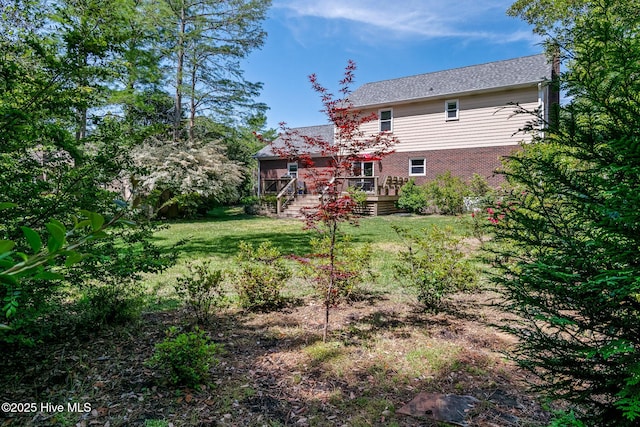 rear view of house with brick siding, stairway, a deck, and a lawn