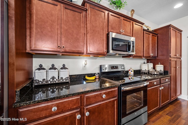 503 Shipyard Ct, Swansboro, NC 28584 - kitchen with dark wood-style flooring, recessed lighting, brown cabinets, dark stone countertops, and stainless steel appliances
