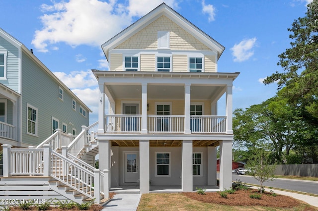 view of front of property with a porch, stairway, a balcony, and stucco siding