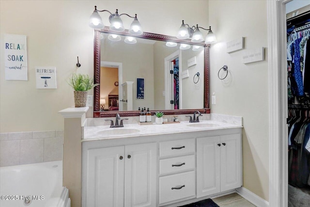 full bathroom featuring double vanity, a spacious closet, a sink, and a garden tub