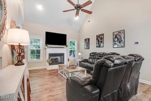 living room with plenty of natural light, high vaulted ceiling, ceiling fan, and light wood-style flooring