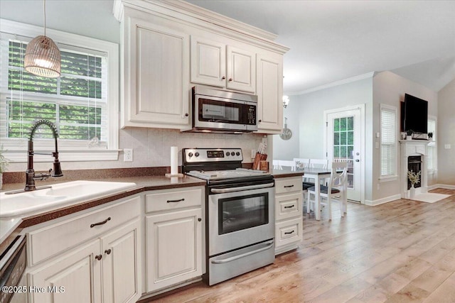 kitchen featuring crown molding, appliances with stainless steel finishes, plenty of natural light, and a sink