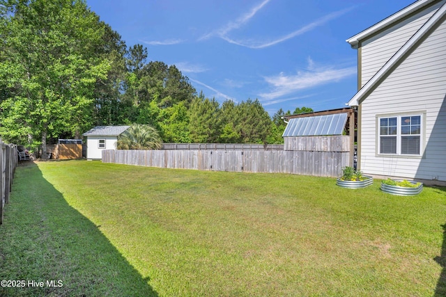 view of yard with a fenced backyard, an outbuilding, and a storage shed